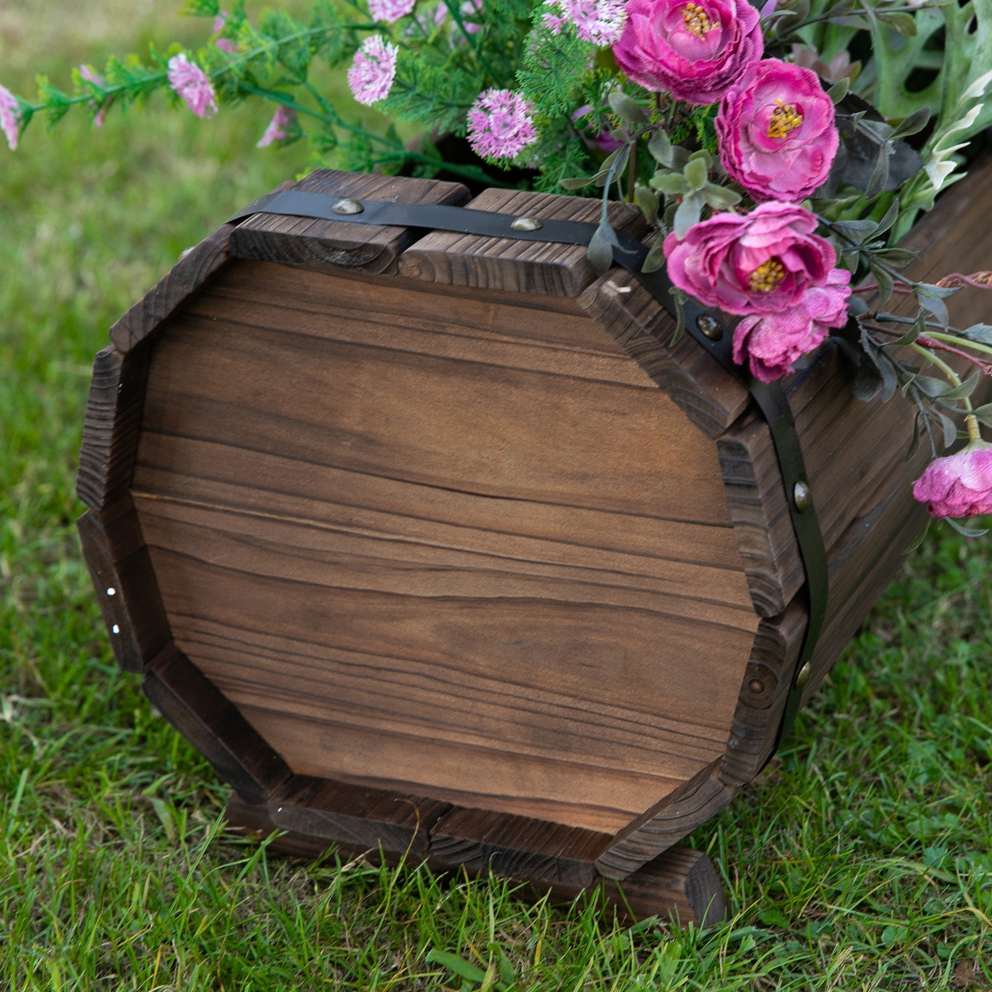 Dark brown solid wood planter box with black leather straps and pink flowers in carbonized colour for flower beds