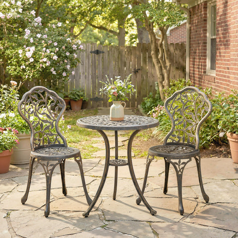 Black wrought iron bistro set with two chairs featuring ornate leaf legs and under-shelf for outdoor patio use