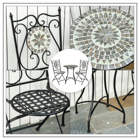 Black wrought iron garden bistro set with round mosaic tile table and two folding chairs in gray and white tones