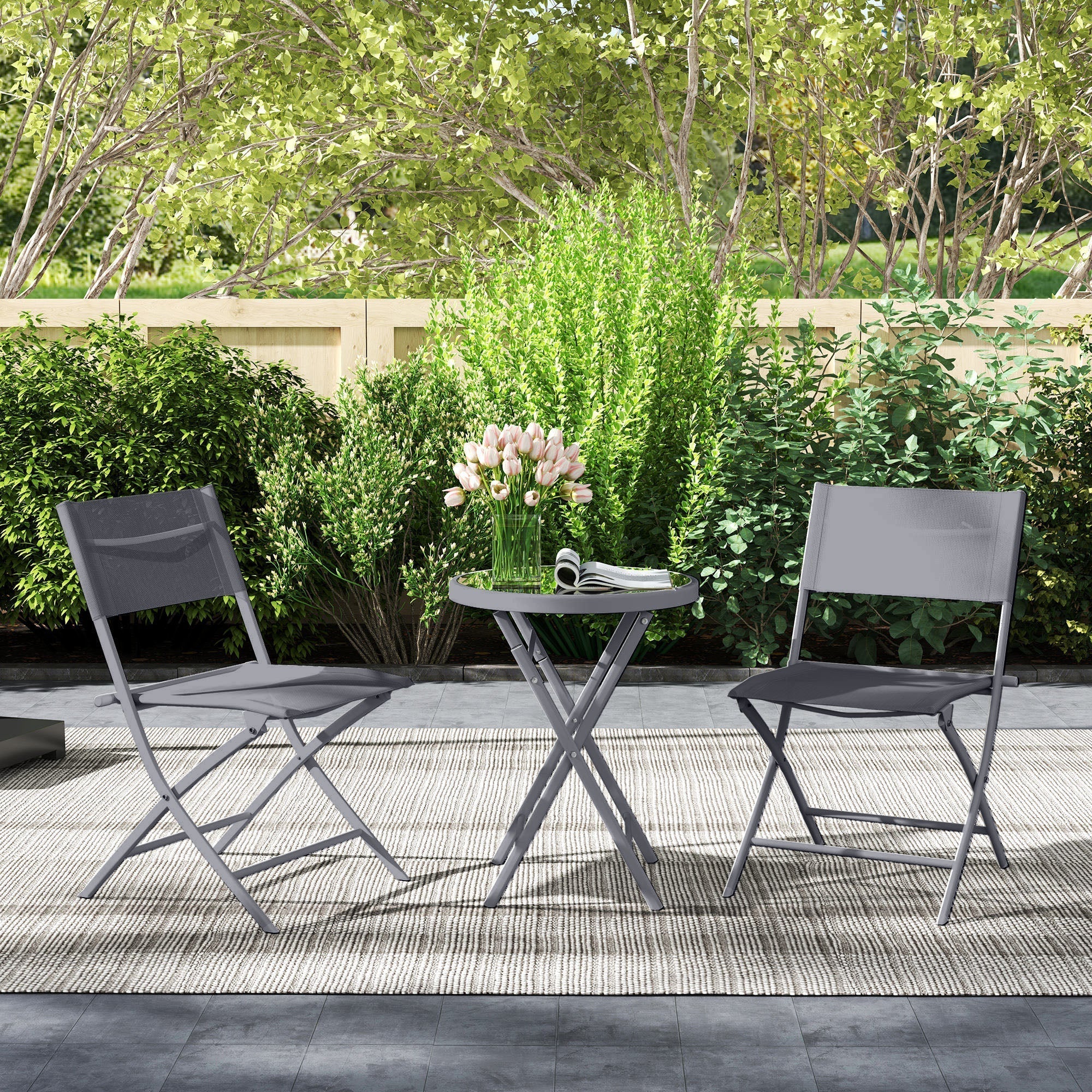 Gray metal folding outdoor bistro set with round tempered glass top and pink tulips on breathable mesh chairs