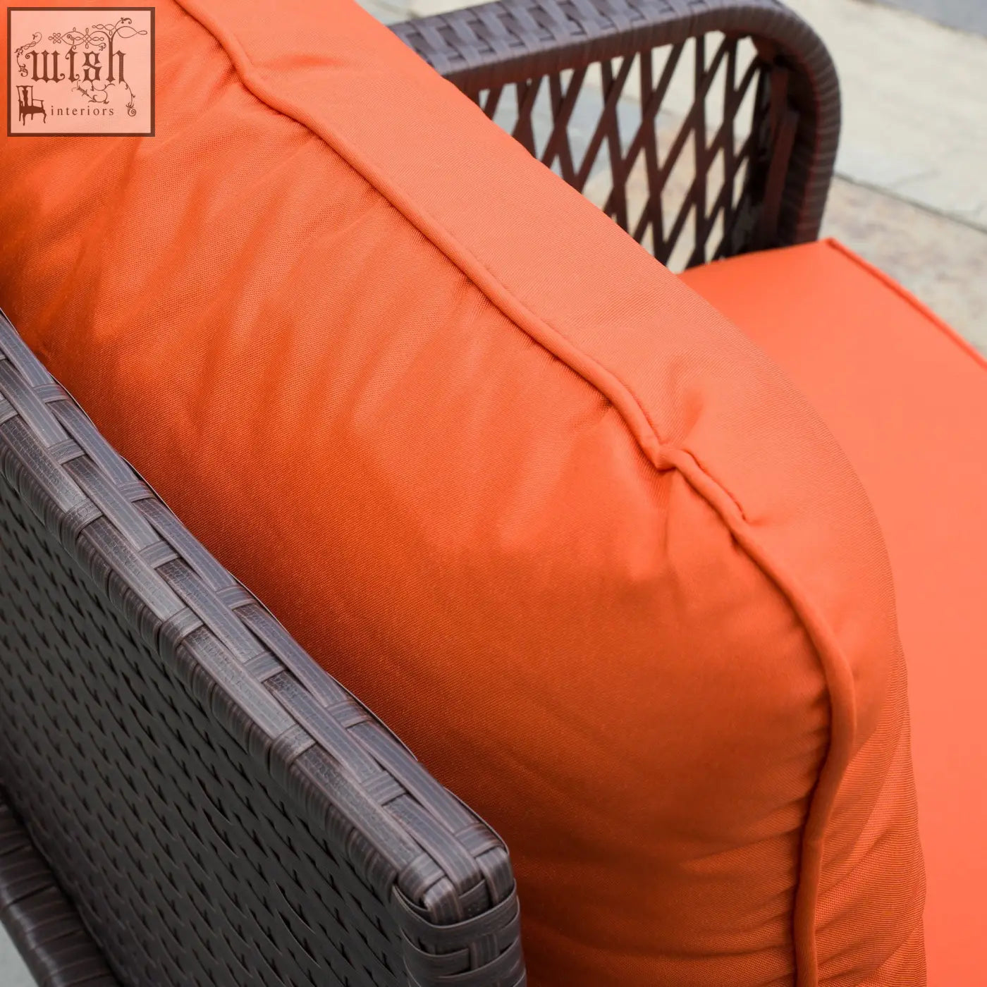 Bright orange cushion with textured fabric on dark brown wicker chair in outsunny rattan bistro set with tempered glass coffee table holding place