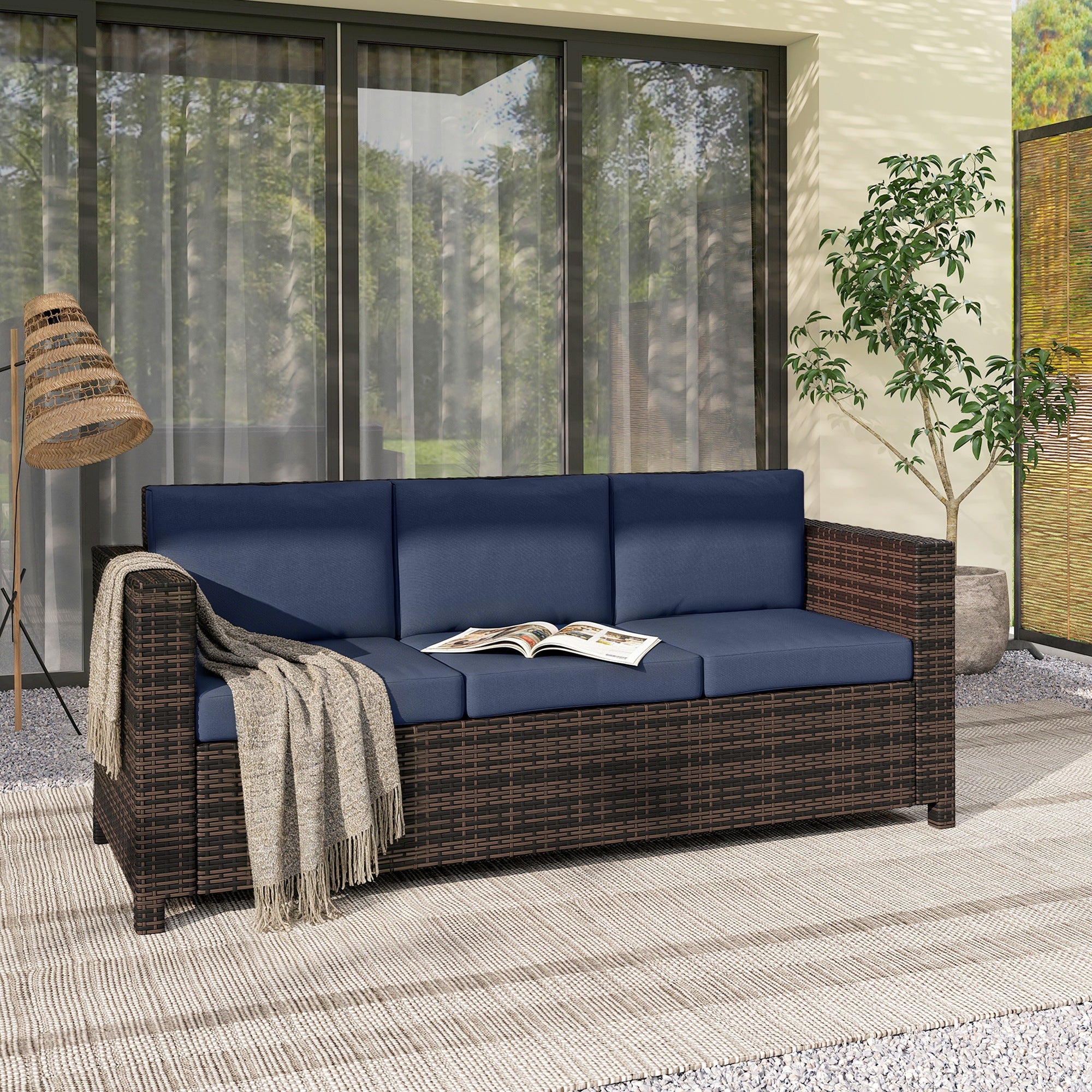 Dark brown rattan sofa with dark blue cushions and beige throw blanket for three persons outdoor use