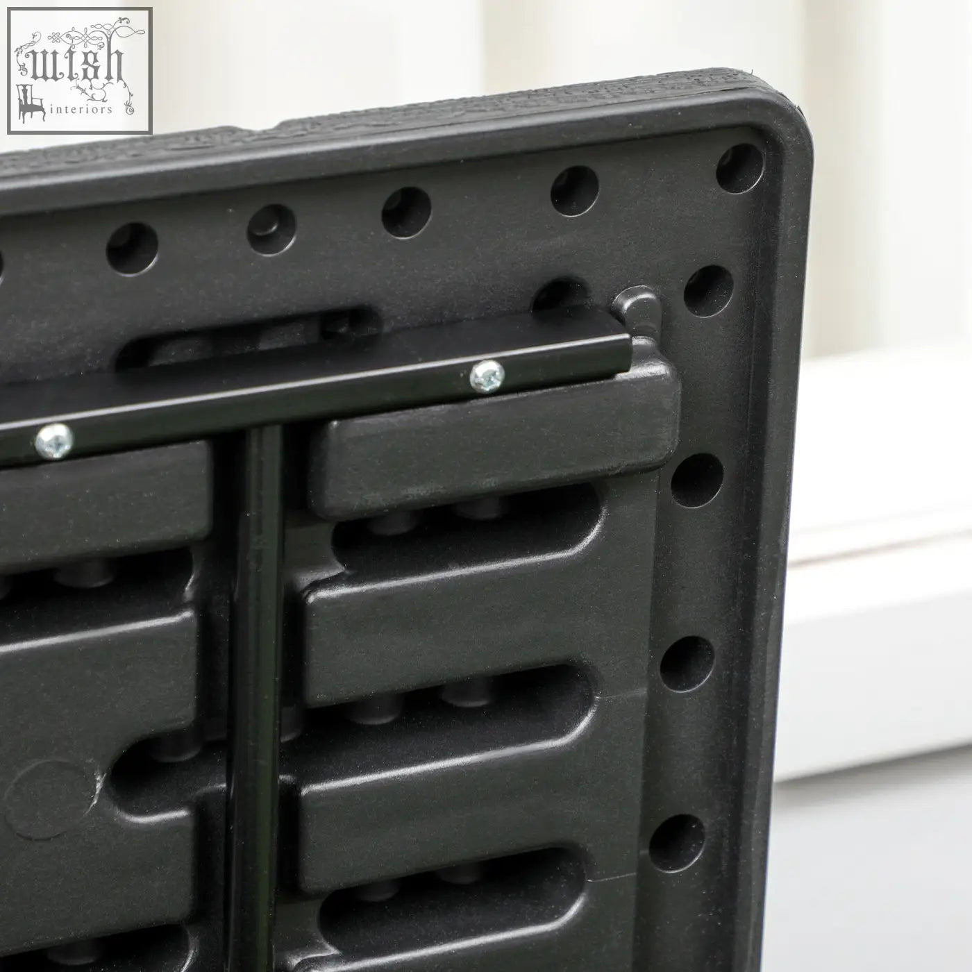 Black plastic folding table with textured surface and reinforced corners for outdoor storage box setup