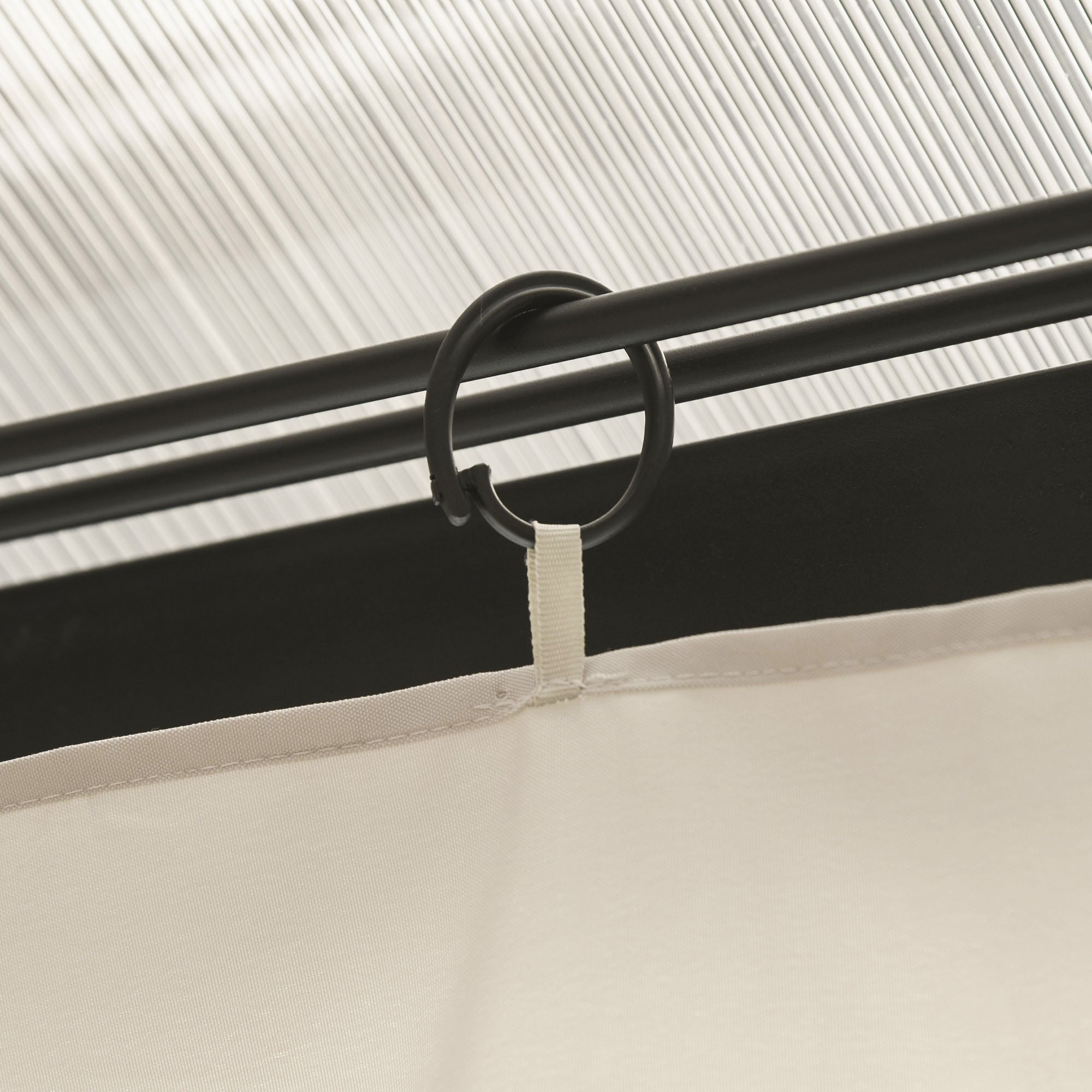 Black plastic curtain ring with white fabric tab securing cream gazebo curtain to black rod for gazebo frame use