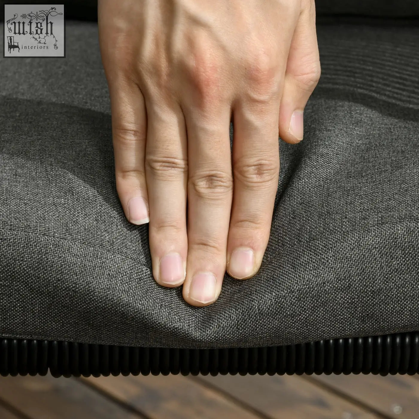 A hand resting on a dark gray cushion with black ribbed edge from outsunny seater rattan cube garden furniture set
