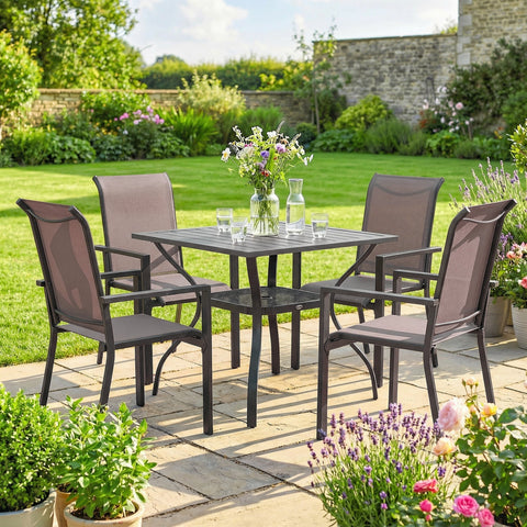 Dark gray metal outdoor dining set with breathable mesh stackable chairs and slatted table on stone patio with flowers