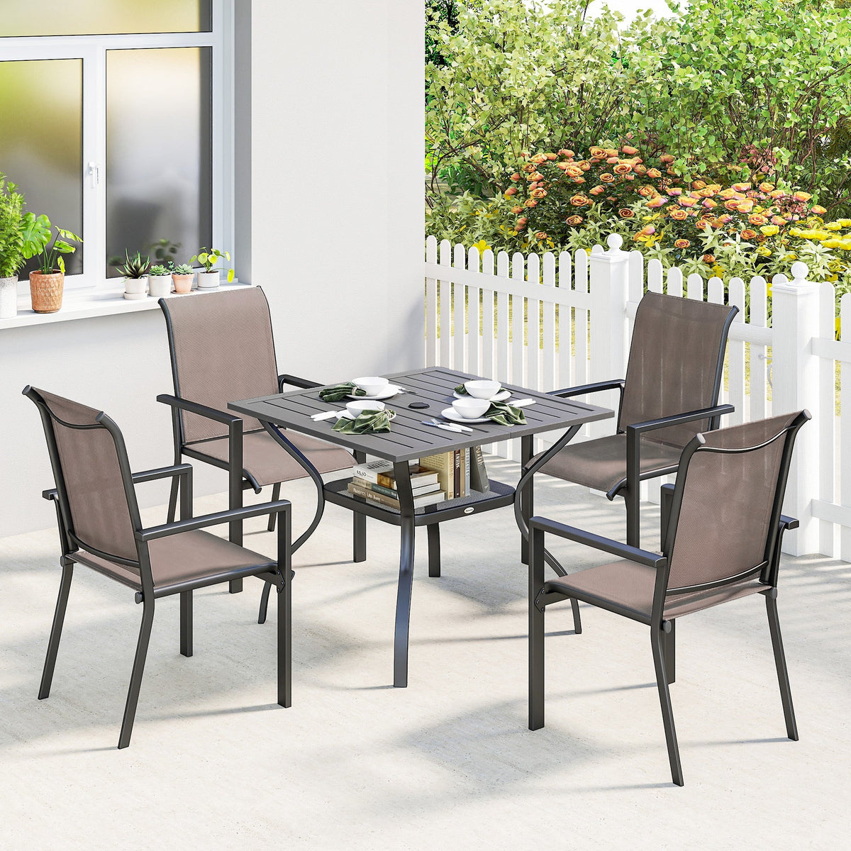 Set of four dark brown breathable mesh stackable chairs with black metal frames around matching outdoor dining table