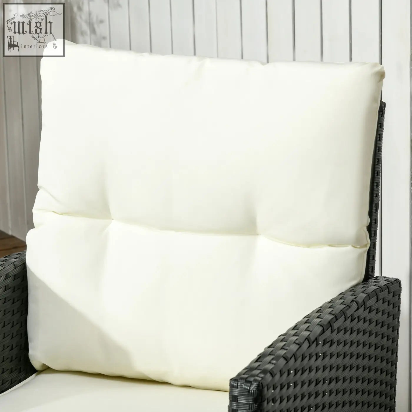 Cream-colored plush cushion with tufted design on dark woven rattan garden sofa with steel frame and coffee table
