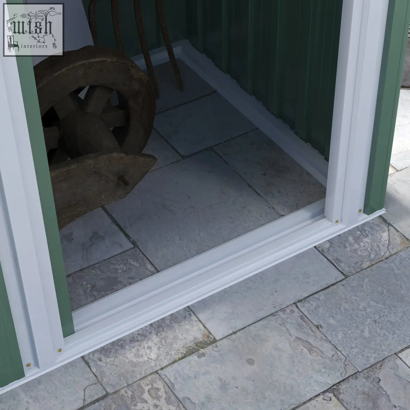 White plastic threshold trim along the base of green outsunny storage shed sliding door in galvanised steel frame