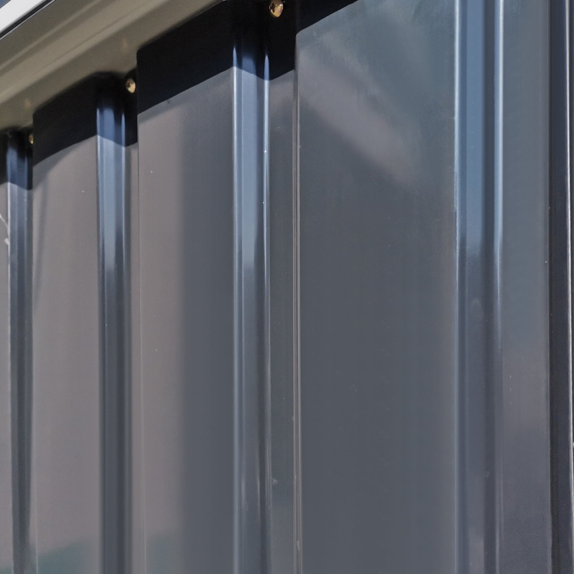 Gray corrugated metal garden storage shed with black trim gold fasteners and sloped roof for tools and equipment