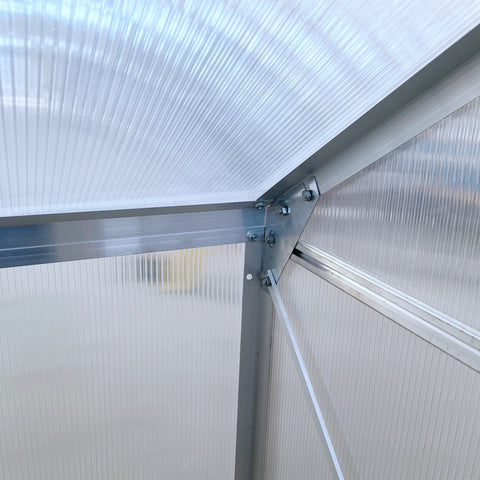 Silver aluminium alloy frame with ribbed translucent polycarbonate panels forming a lean to wall greenhouse corner