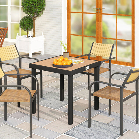 Black metal frame garden dining table with light brown wooden top and wicker cushions on matching chairs outdoors