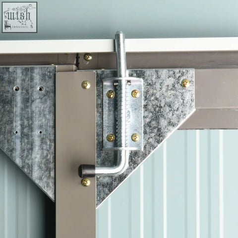 Galvanized metal gate latch with brass screws and curved handle on grey outsunny garden shed with two doors and air vents