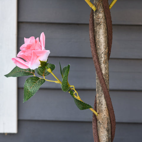 Outsunny artificial pink rose with yellow stem and green leaves in cement soil for indoor outdoor decor