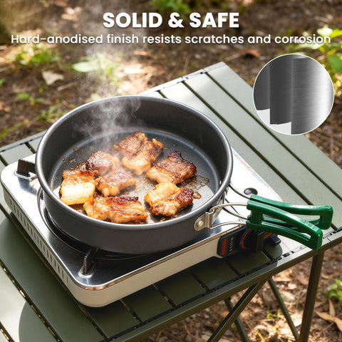 Black hard-anodized frying pan with green anti-scald handle on portable stove from Outsunny camping cooking set