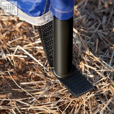 Black metal steel poles hold a blue fabric canopy with black strap in dry grass for outsunny camping windbreak use