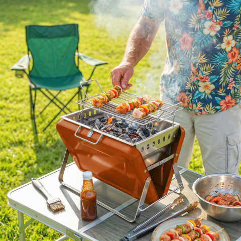 Orange outsunny portable charcoal grill with stainless steel accents and tilting grate for easy add charcoal use