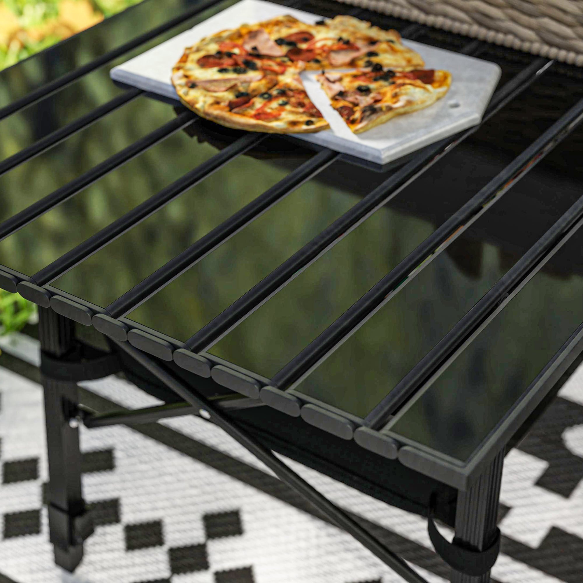 A black glass-top outsunny camping table with metal frame, oxford cloth storage basket, and height adjustable legs
