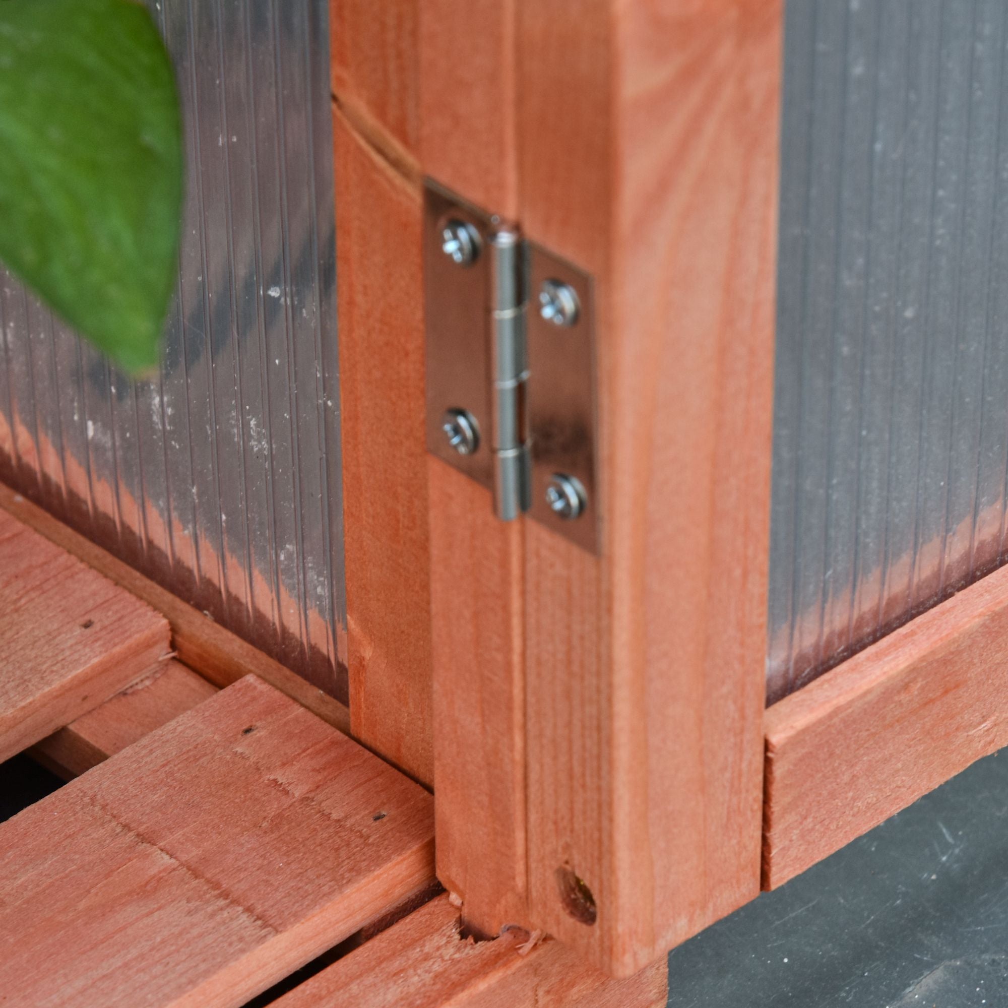 Silver metal hinge with four screws mounted on reddish-brown wood frame of outsunny cold frame with adjustable shelves