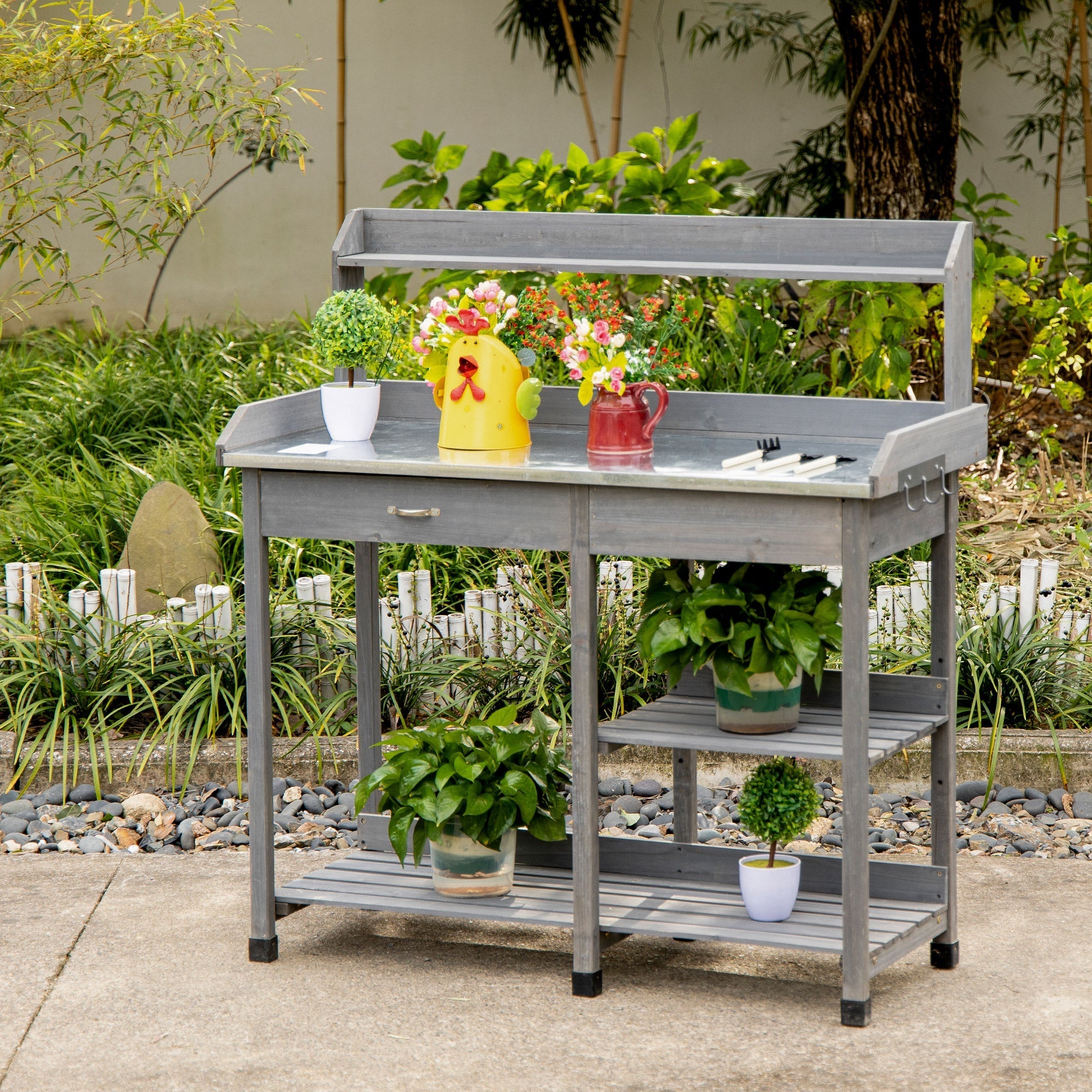 Gray wooden outsunny garden potting table with galvanized metal top, drawer, shelves, and colorful watering cans