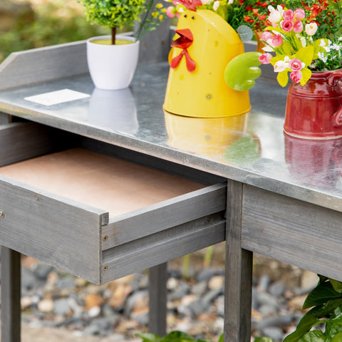 Gray wooden garden potting table with galvanized metal countertop and open drawer for outdoor garden workstation