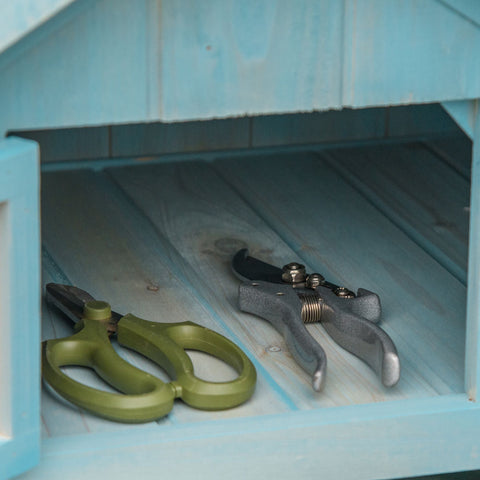 Olive green-handled pruning shears with metallic blades on light blue shelf in outsunny blue storage shed for garden tools
