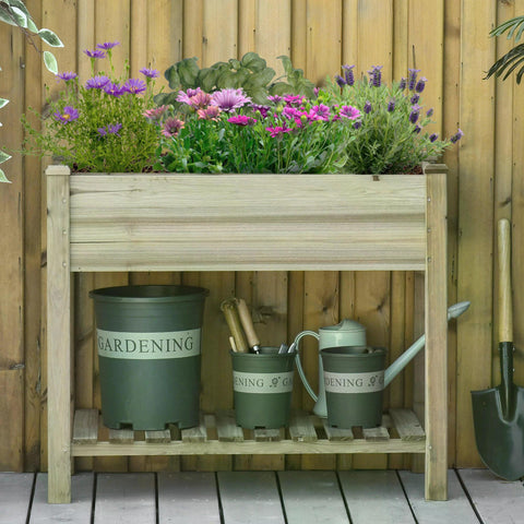 Light-colored fir wood garden planter with legs and storage shelf holding green containers and purple flowers