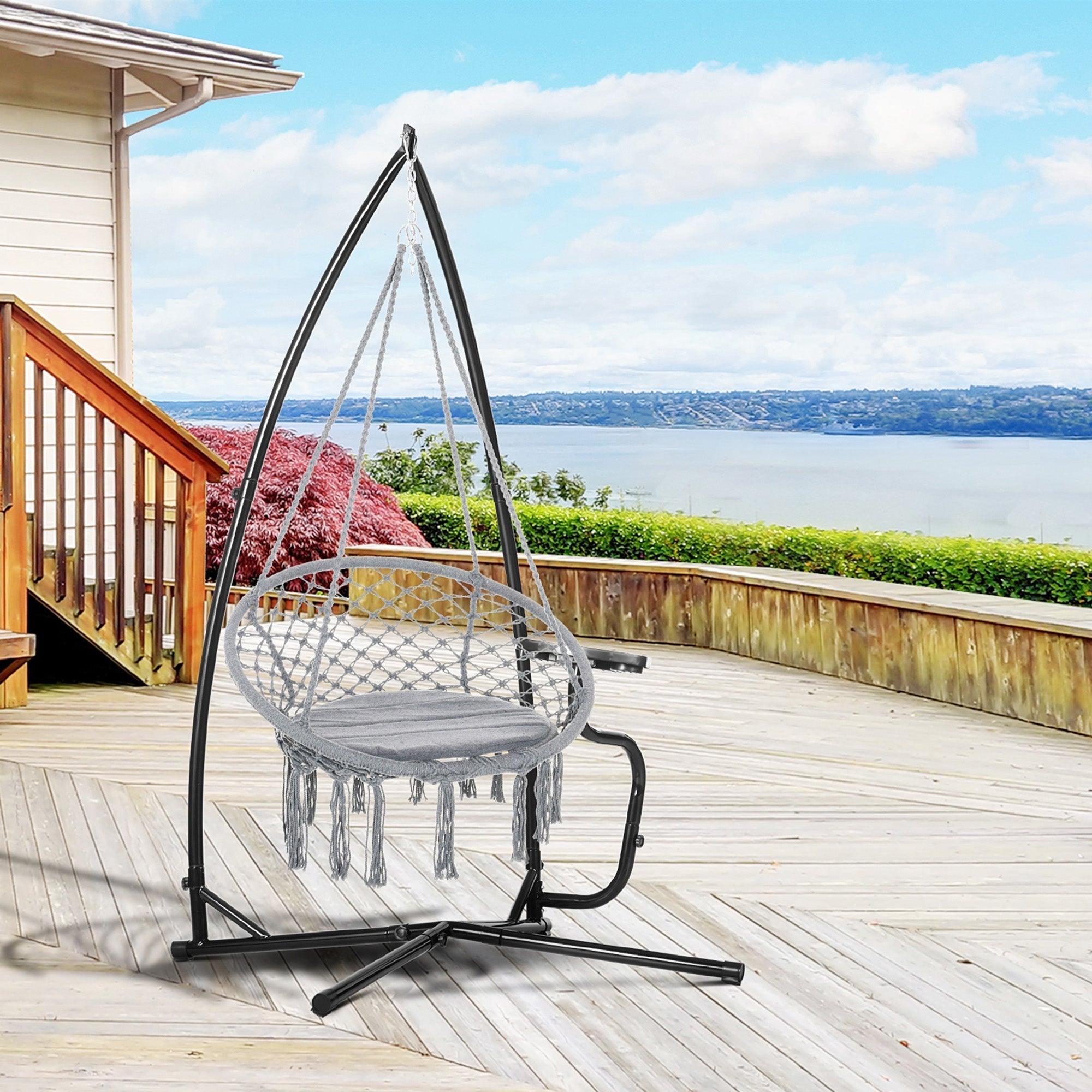 Gray macrame hammock chair with woven net and tassels hanging from a heavy duty black metal hammock chair stand