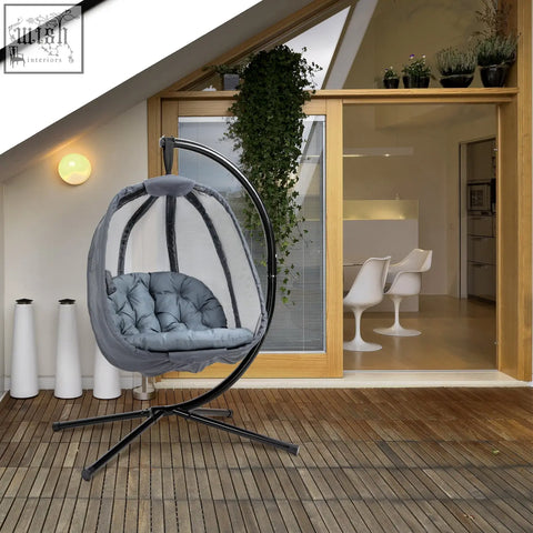 Gray cushioned hanging egg chair with black metal frame and mesh netting for indoor outdoor patio use