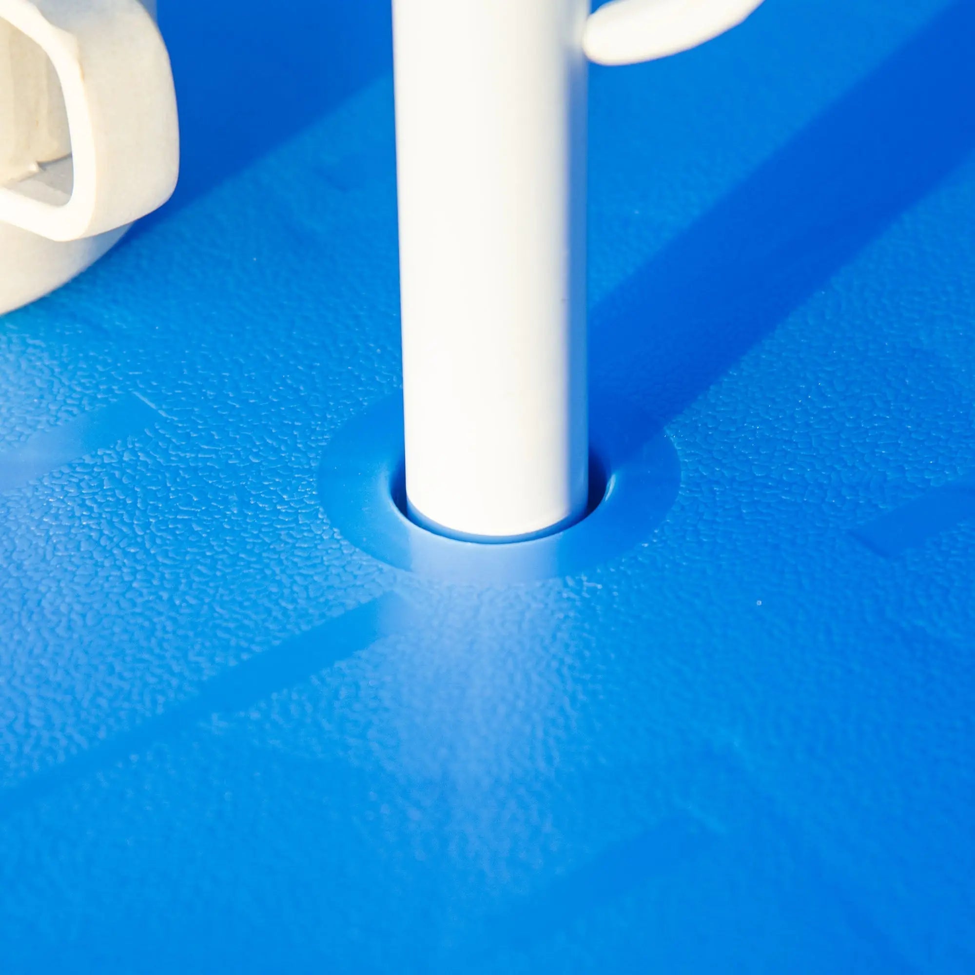White plastic pole inserted into blue textured base of Outsunny kids outdoor bistro table with shark design sun umbrella