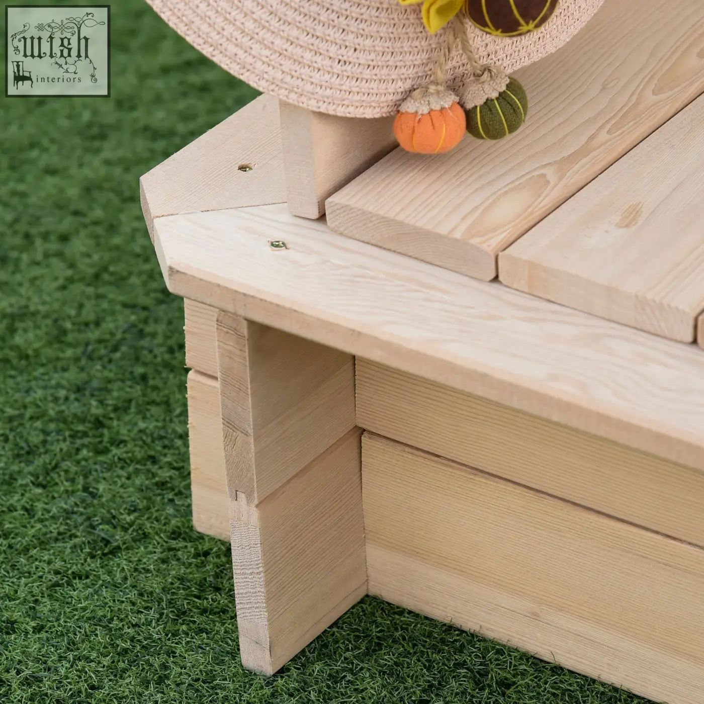 Light-colored fir wood kids sand pit bench with woven straw hat and white canopy for outdoor backyard playset