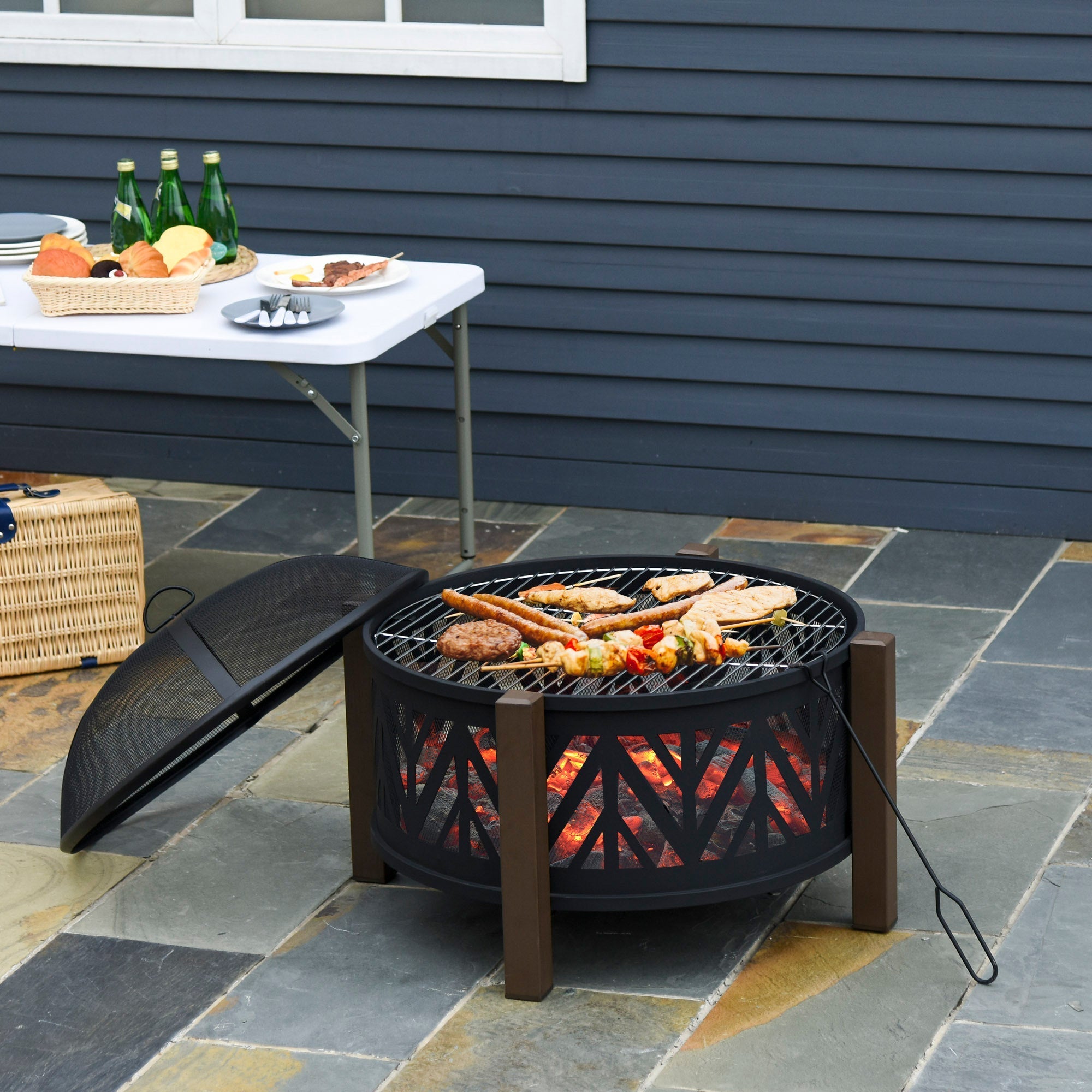 Outsunny black metal fire pit bowl with wooden legs and mesh lid showing glowing embers for food safely grilling outdoors