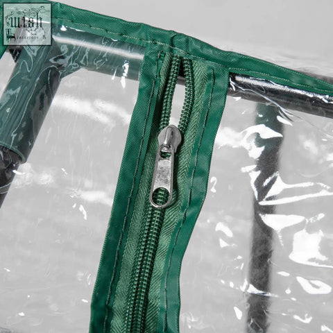 Green fabric zipper with metallic pull tab on mini greenhouse plastic cover for backyard garden planter with zipped windows