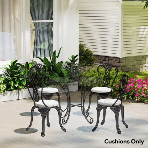 Black wrought iron patio dining set with ornate scrollwork and white outsunny outdoor seat cushions with ties