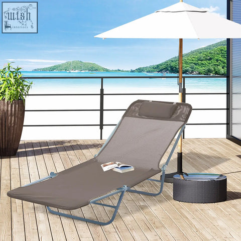 Gray mesh foldable sun lounger with steel frames and headrest pillow on wooden deck under umbrella for outdoor use