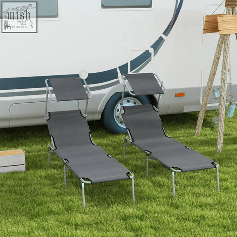 Two grey fabric outsunny reclining sun loungers with metal frames and adjustable backrests on grass by an rv