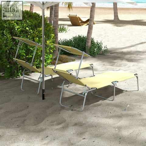 Beige fabric reclining sun lounger set with silver metal frames under white beach umbrella on sandy ground