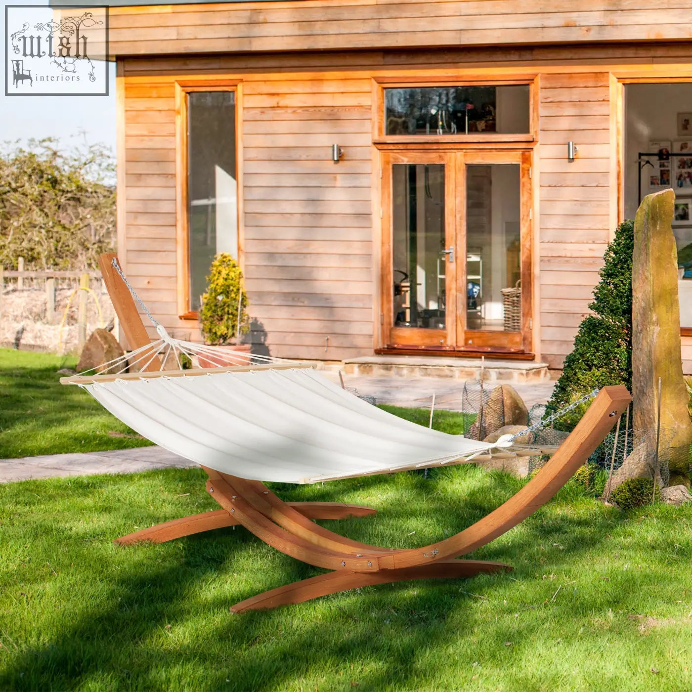 Cream-colored outsunny garden hammock with curved wooden frame and stand hanging between two sturdy patio supports