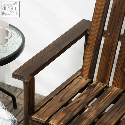 Dark brown adirondack chair made of solid fir wood with carbonised finish featuring slatted seat and sturdy armrests