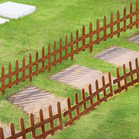 Brown fir wood picket fence with pointed tops and vertical slats for lawn edging and flowerbeds