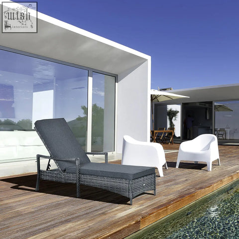 Dark gray wicker lounge chair with mixed grey rattan and seat cushion on wooden deck by pool outdoors