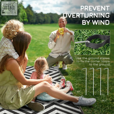 Black fabric strap with metal ground stakes for securing the Outsunny reversible outdoor rug with carry bag