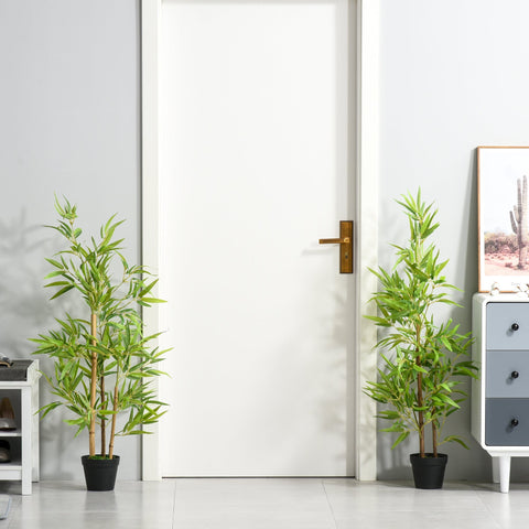 Two green artificial bamboo trees in black pots flanking a white door perfect for indoor outdoor decor