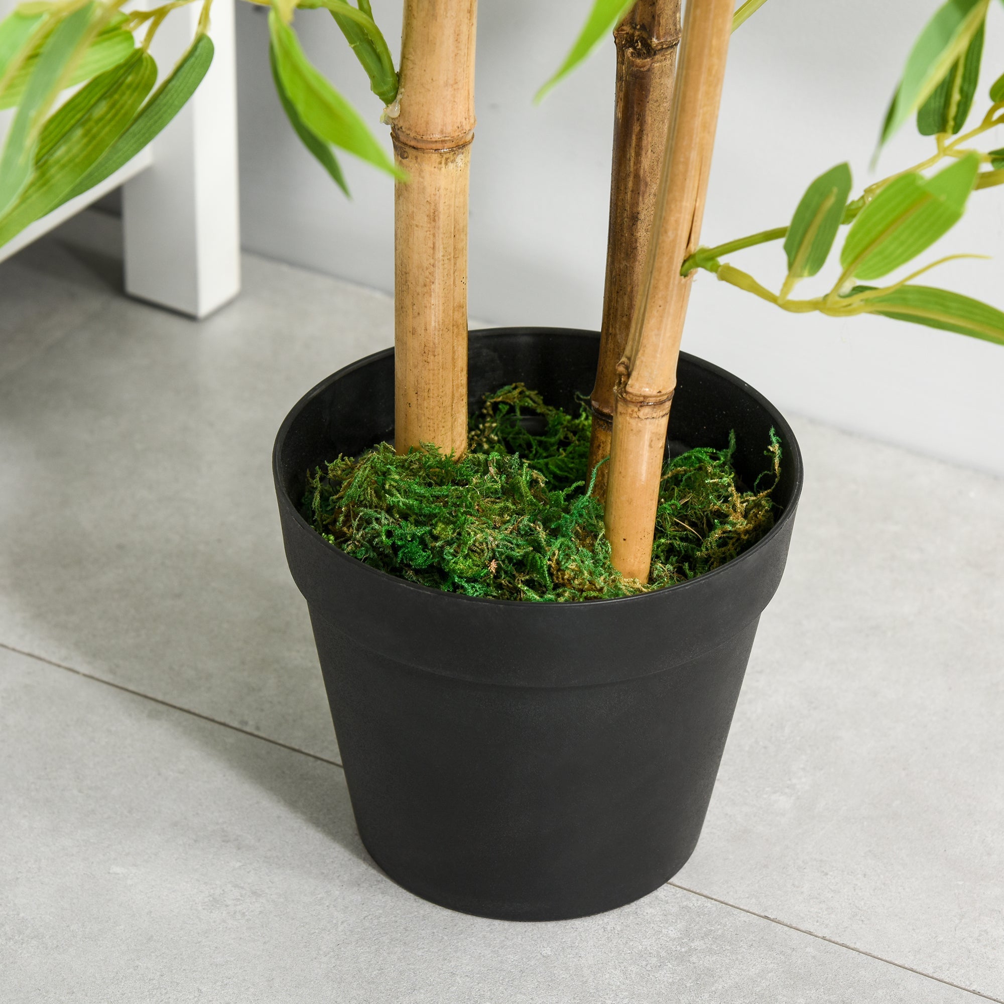 Black plastic pot with green leaves and moss holding 120cm artificial bamboo tree for indoor outdoor use