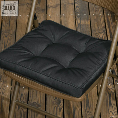 Black quilted garden seat cushion with plush padding, stitched squares, and two tie fastenings for outdoor seating