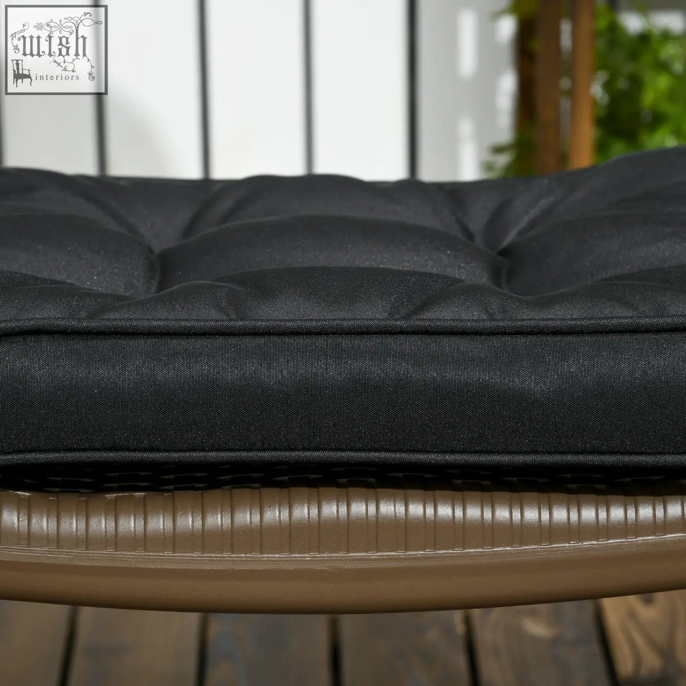 Black tufted outdoor cushion with textured fabric and two tie fastenings for secure outdoor seating comfort
