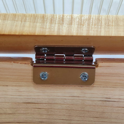 A polished brass hinge with silver screws on the natural wood frame of an outsunny cold frame greenhouse