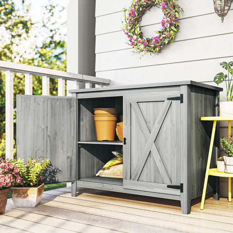 Gray wooden garden shed with rustic barn doors black metal hinges and built-in shelf for outdoor storage