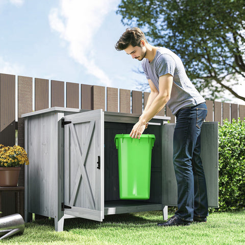 Bright green plastic trash bin inside light grey outsunny wooden garden shed with built-in shelf and barn doors
