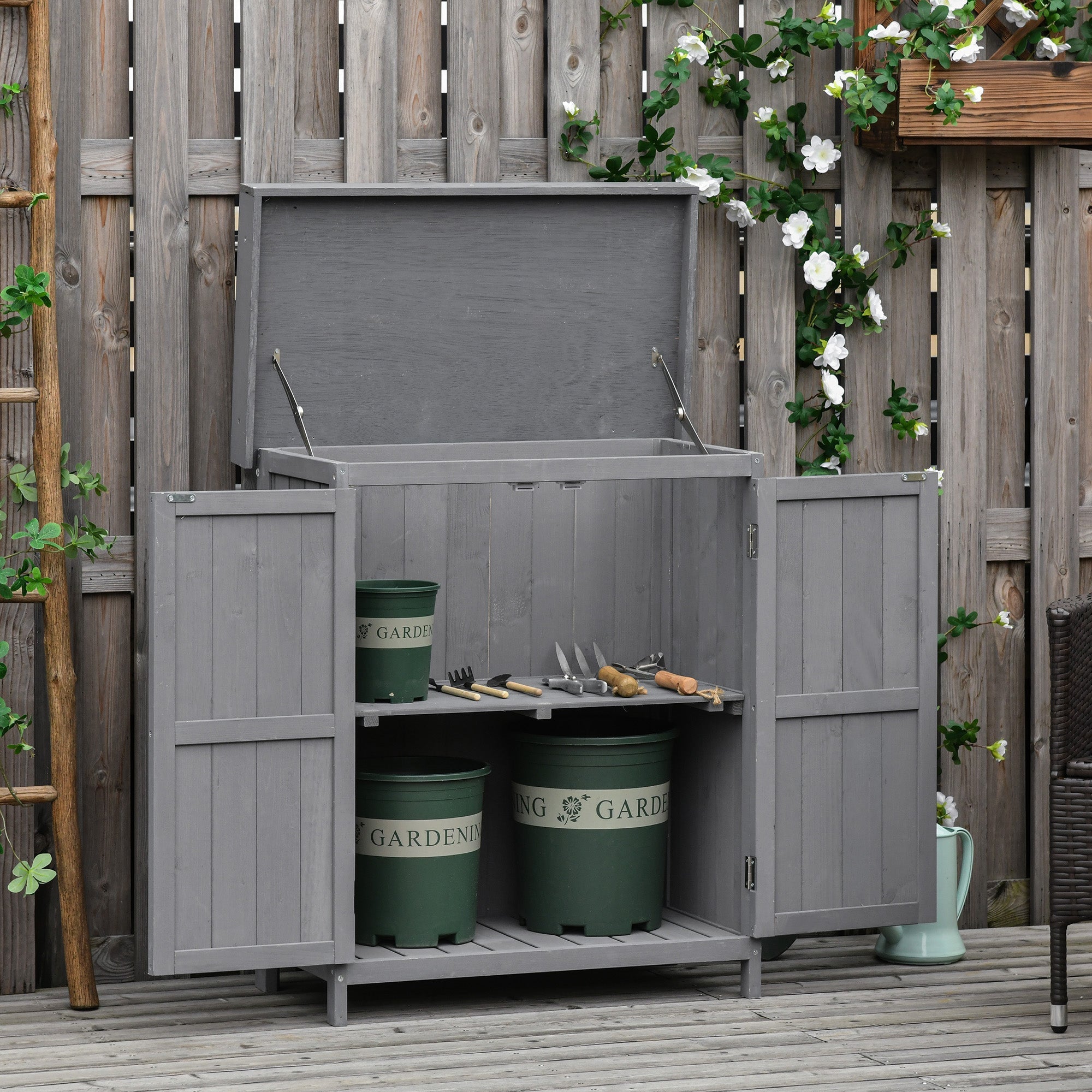 Gray wooden garden storage shed with hinged roof and double doors holding green buckets for outdoor storage